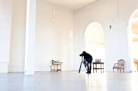 Une grande salle blanche à arcades, un photographe au travail
