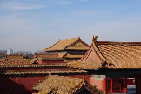 Toits de tuiles dorées et murs rouges de la Cité interdite au soleil couchant